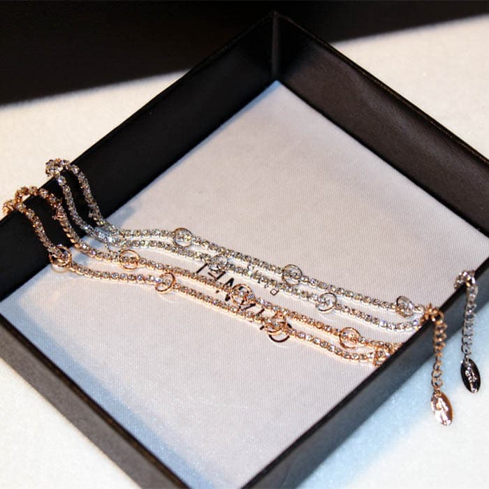 Pulseira feminina elegante e sofisticada com strass em formato de círculo e detalhes dourados.