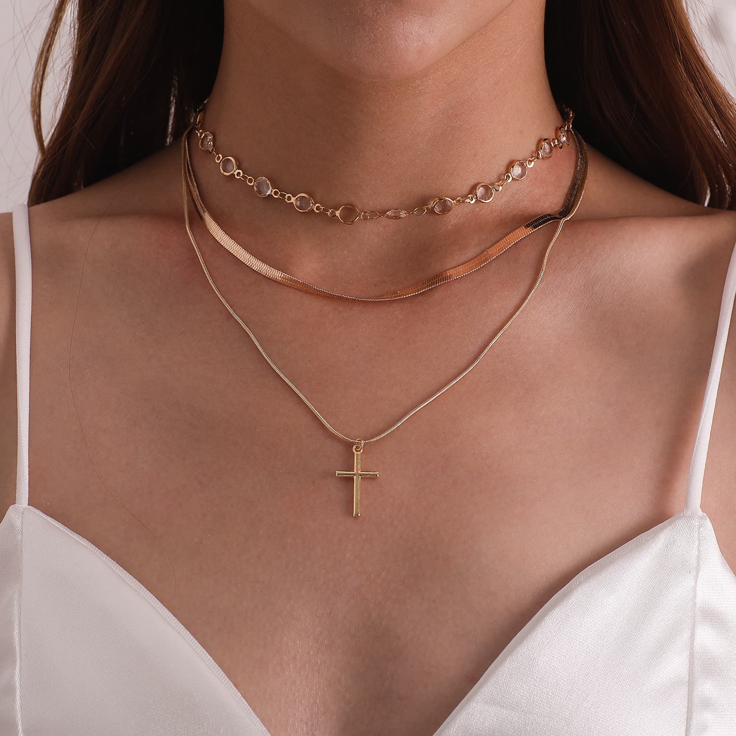 Colar feminino moderno com pingente de cruz e strass.